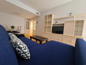 sala de estar con sofá azul y TV en Dos Torres Edificio de los Arcos 3 - Plaza de Parking Incluida, en Zaragoza
