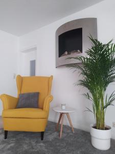 uma cadeira amarela numa sala de estar com uma planta em Main Idyll em Frickenhausen