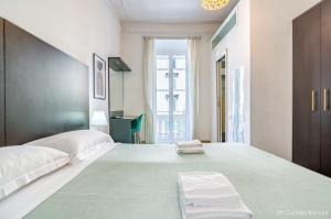 a white bedroom with two beds and a window at El Dorado Colosseum in Rome