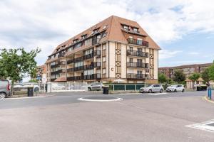 duży apartamentowiec z samochodami zaparkowanymi na parkingu w obiekcie Le Grand Cap w mieście Villers-sur-Mer +4 zdjęcia