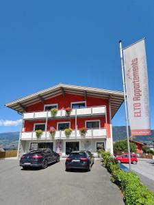 two cars parked in a parking lot in front of a building at Elto Appartements in Kaprun