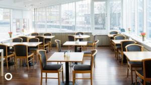 a restaurant with tables and chairs and windows at Center Hotels Skjaldbreid in Reykjavík