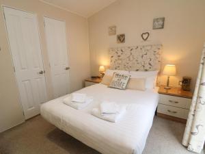 une chambre avec un grand lit blanc avec deux serviettes dans l'établissement Waterside Lodge, à Carnforth