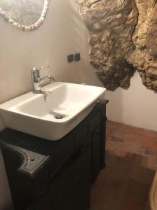 a bathroom with a white sink and a stone wall at La Casa nel Castellare in Campiglia dʼOrcia