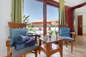 un soggiorno con tavolo, sedie e una grande finestra di Villa Brisamar19 a Corralejo