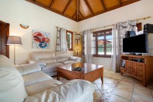 Una sala de estar con un sofá y un televisor. en Villa Brisamar19, en Corralejo