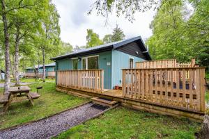 a tiny house with a deck and a picnic table at Bracken Lodge 7 with Hot Tub in Belladrum