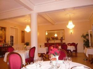 uma sala de jantar com mesas brancas e cadeiras vermelhas em La Cameline em Plougasnou