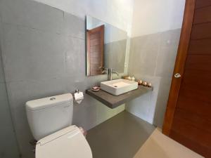 a bathroom with a toilet and a sink at Umah Nik Kepitu in Gianyar