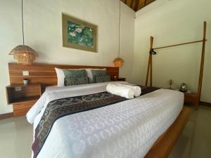 a bedroom with a large bed with a wooden headboard at Umah Nik Kepitu in Gianyar