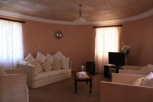 uma sala de estar com sofás brancos e uma televisão em Hotel Mount Maluti - Lesotho em Mohales Hoek