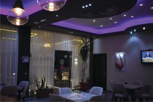 uma sala de jantar com mesas e cadeiras brancas e iluminação roxa em Hotel Jurgen em Lezhë