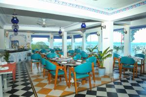 a restaurant with blue chairs and tables and windows at Hotel Darbargarh A Unit of Khamma Ghani A Boutique Hotel in Udaipur