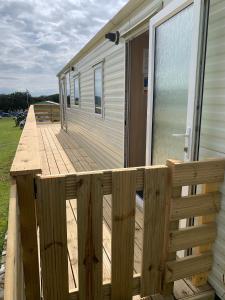 una terraza de madera en el lateral de una casa en TL083 - 2 Bedrooms indoor pool Loch Views fishing Golf Riding Shooting Water Sports 15 min drive to beaches PASSES NOT INCLUDED Most Activities Will Not Be Available Out Of Season Please Check Before Booking, en Newton Stewart