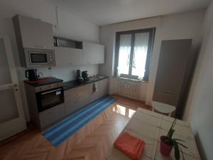 une cuisine avec des placards blancs, une table et une fenêtre dans l'établissement Casa Battisti, à Sondrio