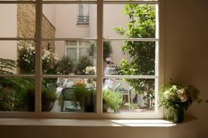 パリにあるル クロ メディシスの鉢植えの植物が植えられたパティオの景色を望む窓