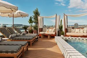 a rooftop patio with lounge chairs and a swimming pool at The Hoxton, Poblenou in Barcelona