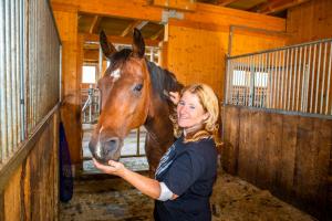 a woman standing next to a horse in a barn at Bauernhof Lehengut in Pfarrwerfen