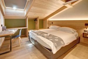 a bedroom with a large bed and a desk at Aria di Casa Piazzi in Valdisotto