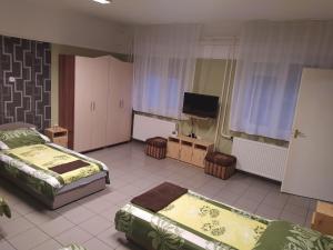 a bedroom with two beds and a flat screen tv at Pingpong Apartman in Soltvadkert