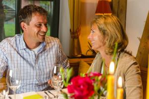 a man and woman sitting at a table with wine glasses at Golfhotel Gut Apeldör in Hennstedt