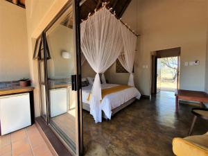 a bedroom with a bed with a canopy at Masorini Bush Lodge in Phalaborwa