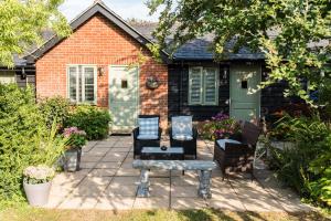 a patio with two chairs and a bench in front of a house at The Foxes Den in Assington