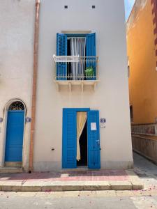 a building with blue doors and a balcony at Bilocale in pieno centro a Marettimo in Marettimo