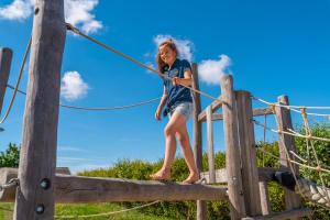 a young girl is walking on a rope bridge at EuroParcs de Woudhoeve in Egmond aan den Hoef