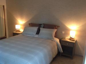 een slaapkamer met een groot bed met 2 lampen bij La Postellerie in Fleury