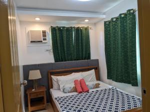 a bed with two red pillows and a green shower curtain at 307 Anabelle Residence at Marina Spatial Condominium in Dumaguete