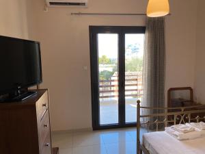 a living room with a television and a sliding glass door at Saronic Hearts in Agioi Theodoroi