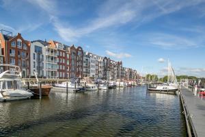 a group of boats docked in a canal with buildings at BB aan de Zuyderzee in Bunschoten