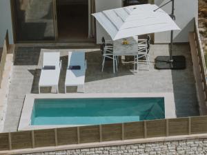 una piscina con sombrilla, mesa y sillas en Paleros Bay Villas en Paleros