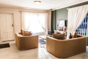 a living room with two chairs and a window at Seagull Hermanus in Hermanus