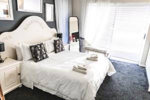 Un dormitorio con una cama blanca y un espejo. en Seagull Hermanus, en Hermanus