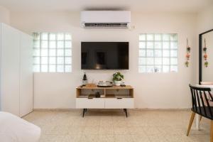 a living room with a tv on a white wall at ירוק באלה - דירת נופש ברמת ישי in Ramat Yishay