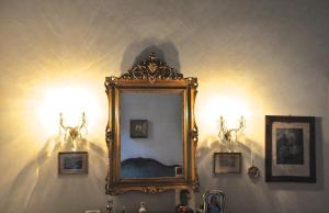 uno specchio su una parete con due luci e un lavandino di Palazzo Altinate - Note di Piano a Padova