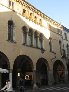 due persone in bicicletta di fronte a un edificio di Palazzo Altinate - Note di Piano a Padova