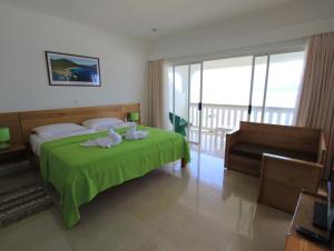 a bedroom with a green bed with towels on it at Marie-France Beach Front Apartments in La Digue