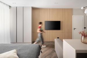 a woman walking through a bedroom with a tv at Savoia Apartment in Labin