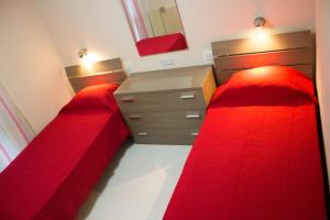 a bedroom with two red beds and a dresser at Apartment Triq is-Silla in Marsaskala