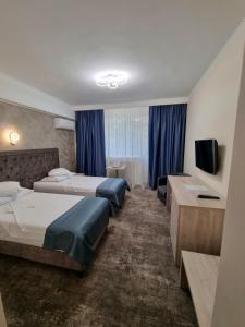 a hotel room with two beds and a television at Hotel Tiara in Ploieşti