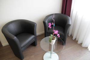 two black chairs and a glass table with flowers at Apado-Hotel garni in Homburg