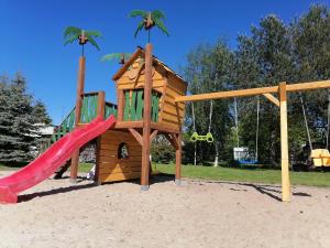 a wooden playground with a slide and a play house at Willa Opal , 250 m do morza in Grzybowo