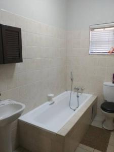 a white bathroom with a tub and a toilet at Ebeneezer Self-Catering Guesthouse in the Lowveld in Sabie
