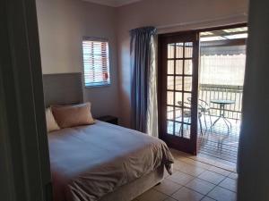 a bedroom with a bed and a door to a balcony at Ebeneezer Self-Catering Guesthouse in the Lowveld in Sabie