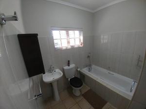 a bathroom with a sink and a toilet and a bath tub at Ebeneezer Self-Catering Guesthouse in the Lowveld in Sabie