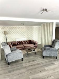 a living room with a brown couch and two chairs at Hotel City Break in Galaţi