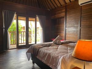 a bedroom with a bed in a room with windows at Mangrove Beach Hut in Nusa Lembongan